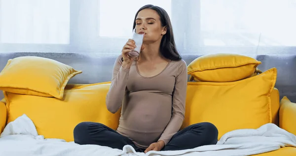 Pregnant woman drinking milk in living room — Stock Photo