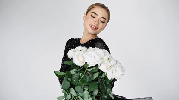 Bailarina sonriente mirando ramo de rosas en gris - foto de stock