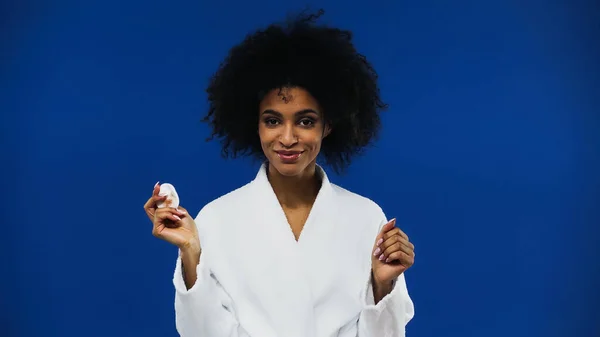 Sorrindo afro-americana segurando algodão pad isolado em azul — Fotografia de Stock