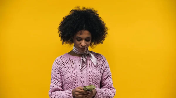 African american woman holding dollars isolated on yellow — Stock Photo
