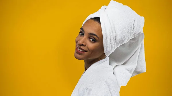 Smiling african american woman in towel and bathrobe isolated on yellow — Stock Photo