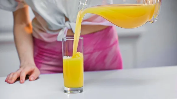 Vista cortada da mulher derramando suco de laranja fresco em vidro — Fotografia de Stock