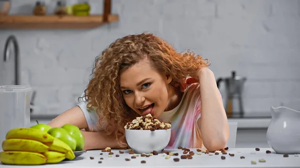 Mulher encaracolado comer pilha de flocos de milho na tigela — Fotografia de Stock