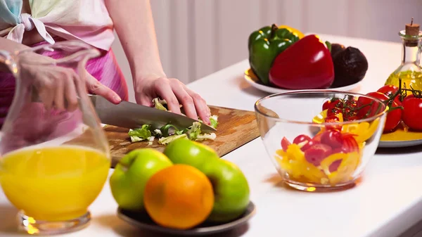 Cropped view of woman cutting lettuce on chopping board — Stock Photo