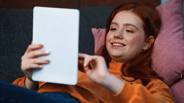 Smiling teenager using digital tablet on blurred foreground at home — Stock Photo