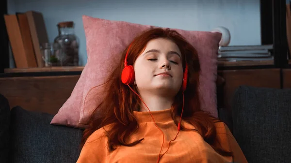 Menina em fones de ouvido relaxante em travesseiros em casa — Fotografia de Stock