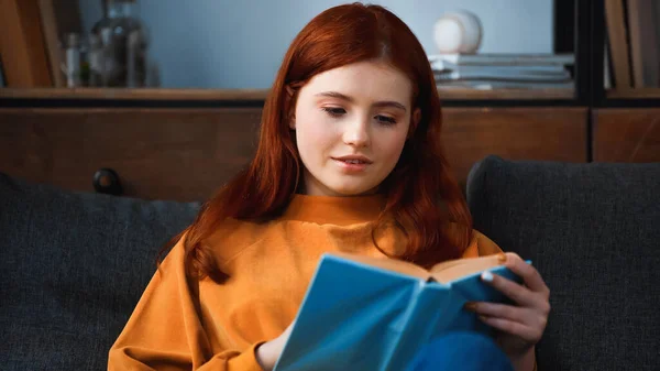 Девочка-подросток читает книгу на размытом переднем плане — стоковое фото