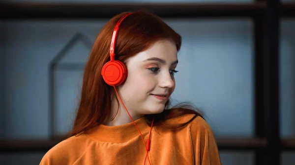 Adolescente pelirroja con auriculares en casa - foto de stock