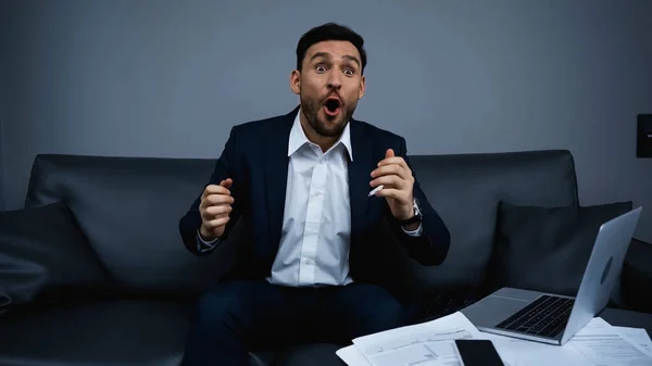 Amazed businessman sitting near devices and documents in hotel — Stock Photo