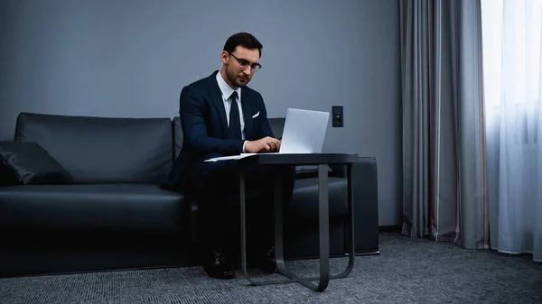 Uomo d'affari che utilizza il computer portatile in una moderna camera d'albergo — Foto stock