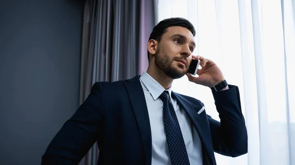 Businessman in formal wear talking on smartphone in hotel — Stock Photo