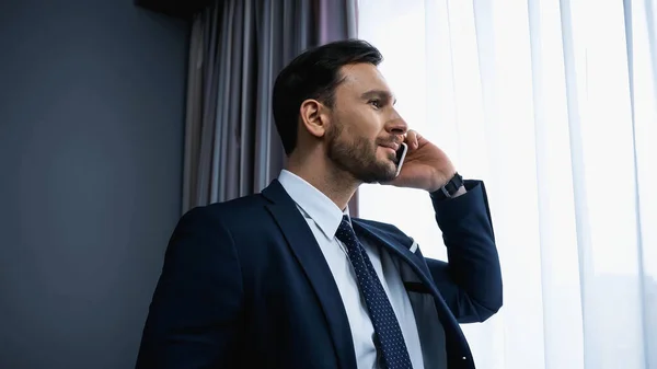 Businessman talking on smartphone in modern hotel room — Stock Photo