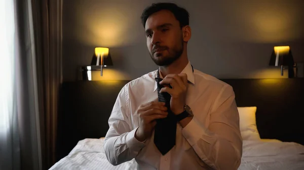 Empresário vestindo gravata no quarto de hotel moderno — Fotografia de Stock