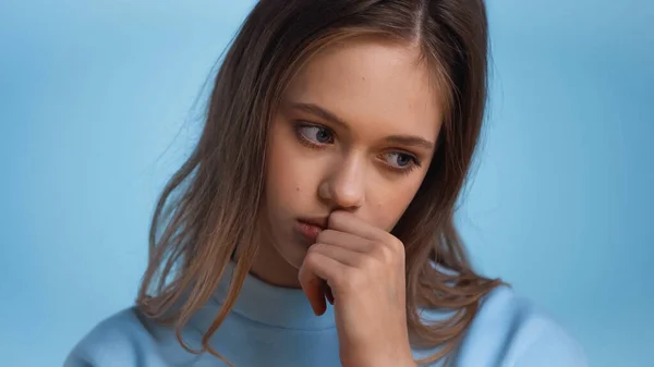 Teenage girl in soft sweatshirt thinking and looking away isolated on blue — Stock Photo