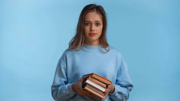 Дівчина-підліток в сорочці тримає книги ізольовані на синьому — стокове фото