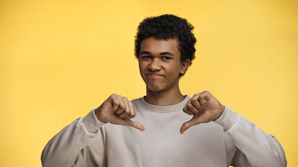 African american teenage boy showing dislike isolated on yellow — Stock Photo