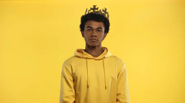 African american teenage boy in hoodie and crown isolated on yellow — Stock Photo
