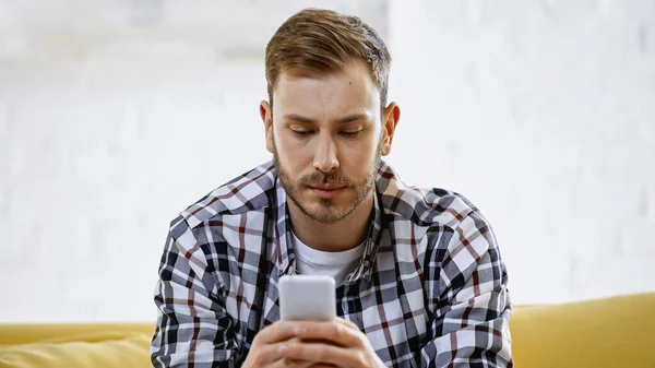 Homem barbudo em checkered camisa mensagens no smartphone — Fotografia de Stock