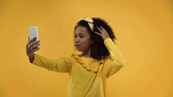 Rizado africano americano chica tomando selfie aislado en amarillo - foto de stock