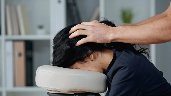 Masajista haciendo masaje en la cabeza a mujer de negocios en la oficina - foto de stock