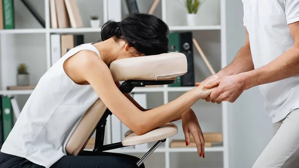 Masseur faisant massage des mains à la femme d'affaires sur chaise de massage au bureau — Photo de stock