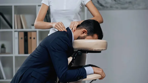 Masseur doing neck massage to businessman in suit in office — Stock Photo