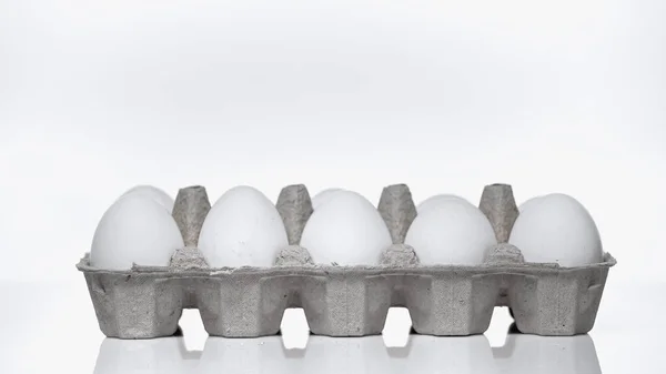 Carton container with raw eggs on white — Stock Photo