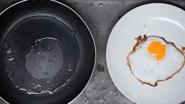 Vista dall'alto di uovo fritto su piatto bianco vicino a padella per friggere — Foto stock