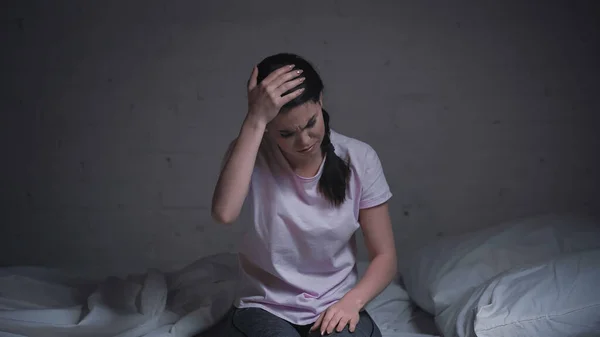 Morena joven que sufre de dolor de cabeza en la noche - foto de stock
