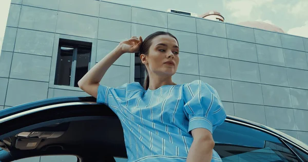 Junge brünette Frau in blauer Bluse posiert in der Nähe von Auto — Stockfoto