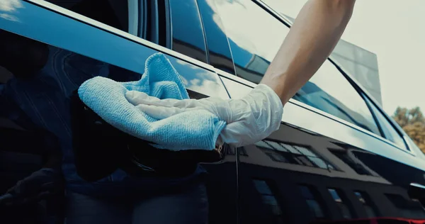 Обрізаний вид жінки в латексній рукавичці дезінфікує двері автомобіля — стокове фото