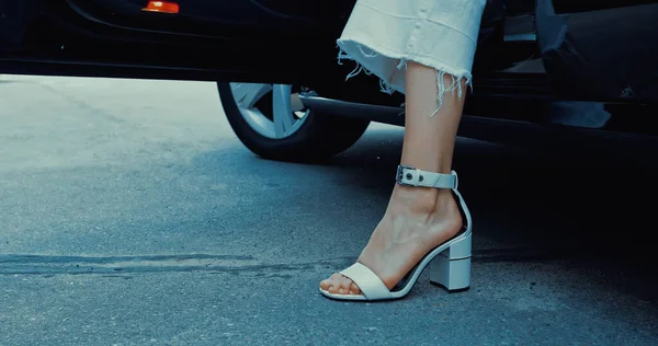 Cropped view of woman in trendy footwear getting out of car — Stock Photo