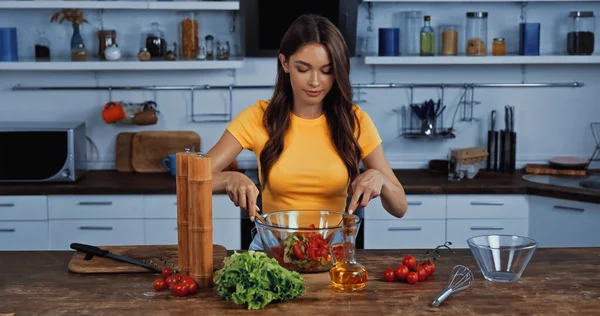 Молода жінка змішуючи свіжий салат на кухні — стокове фото