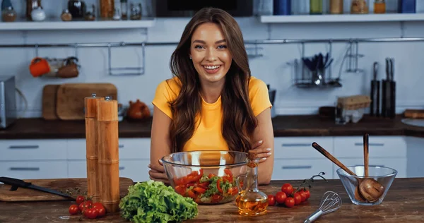 Happy young woman smiling near bowl with fresh mixed salad — Stock Photo