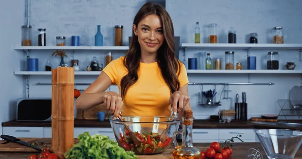 Donna allegra sorridente mentre mescola l'insalata nella ciotola — Foto stock