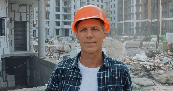 Costruttore in cappello rigido sorridente alla macchina fotografica sul cantiere — Foto stock