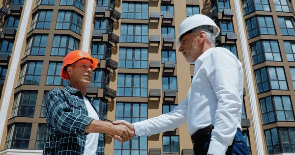 Ingeniero y constructor estrechando la mano y hablando en el sitio de construcción — Stock Photo