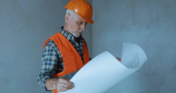 Happy builder looking at blueprint on construction site — Stock Photo