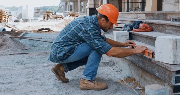 Constructeur mesurant le terrain avec le niveau du bâtiment sur le chantier — Photo de stock