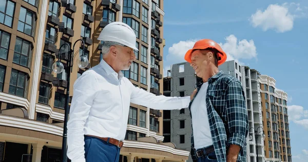 Ingeniero maduro tocando hombro del constructor en el sitio de construcción - foto de stock