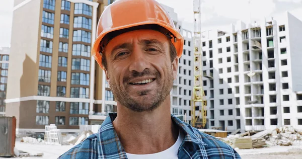 Красивий будівельник посміхається на камеру на будівельному майданчику — стокове фото
