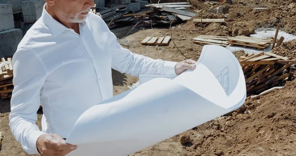 Vue recadrée de l'ingénieur tenant le plan directeur sur le chantier de construction — Photo de stock