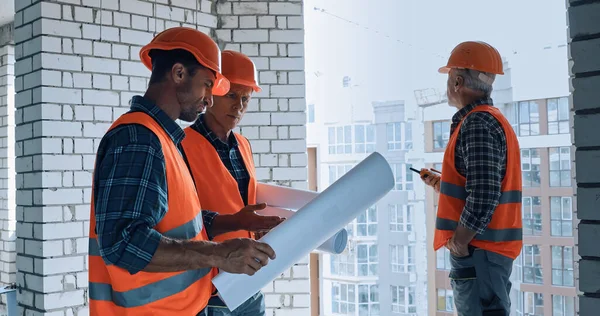 Constructores con planos y walkie talkie trabajando en obra - foto de stock