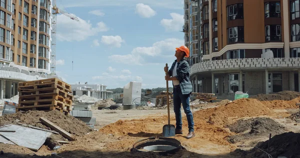 Constructeur d'âge moyen en casque dur tenant la pelle sur le chantier de construction — Photo de stock