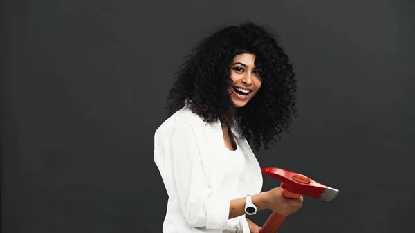 Smiling hispanic woman holding ax isolated on black — Stock Photo