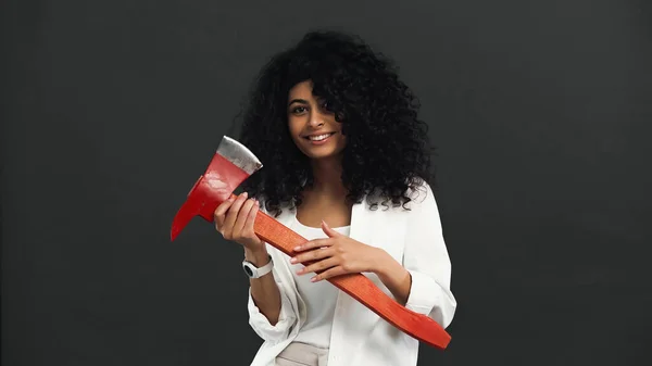 Cheerful hispanic woman holding ax isolated on black — Stock Photo