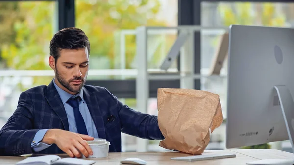 Businessman looking at plastic container with salad — Stock Photo