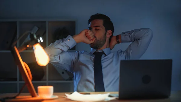 Tired businessman yawning while working late in office — Stock Photo