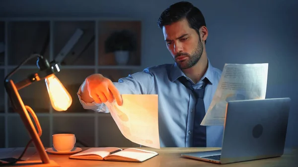 Businessman looking at documents while working late in office — Stock Photo