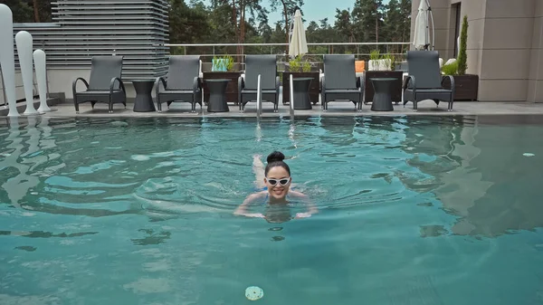 Glückliche junge Frau mit Sonnenbrille schwimmt im Freibad — Stockfoto